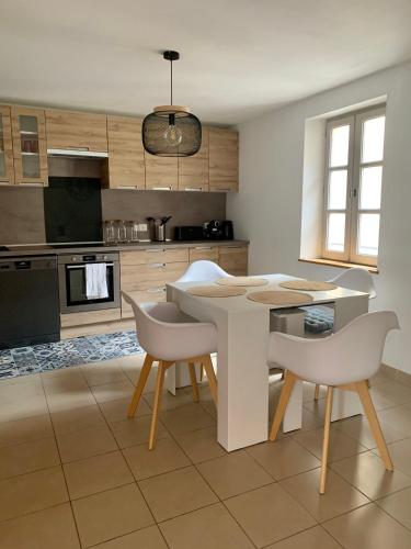 - une cuisine avec une table et des chaises blanches dans l'établissement Au cœur de l’Isle sur sorgue, à LʼIsle-sur-la-Sorgue