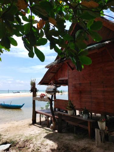 a building on the beach with a bench and a boat at Homestay Pak Ucu 