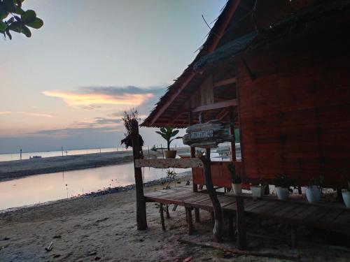 - un bâtiment sur la plage avec une table et un banc dans l'établissement Homestay Pak Ucu, 