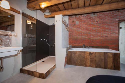 uma casa de banho com uma banheira ao lado de uma parede de tijolos em Norgerbrink em Norg