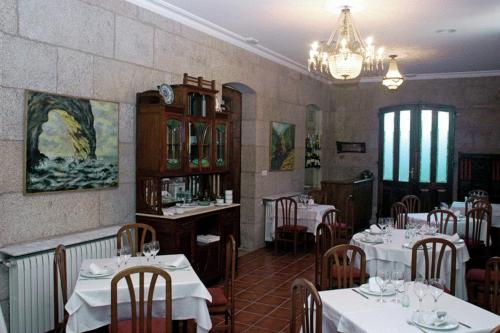 a restaurant with white tables and chairs and a chandelier at Pazo Almuzara in Boborás