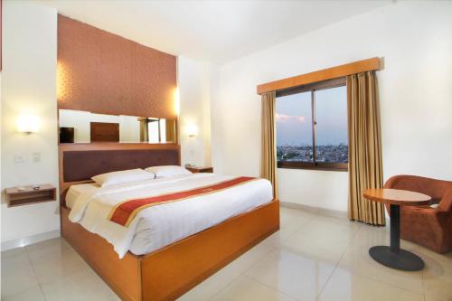 een slaapkamer met een bed, een bureau en een raam bij Hotel Bisanta Bidakara Tunjungan in Surabaya