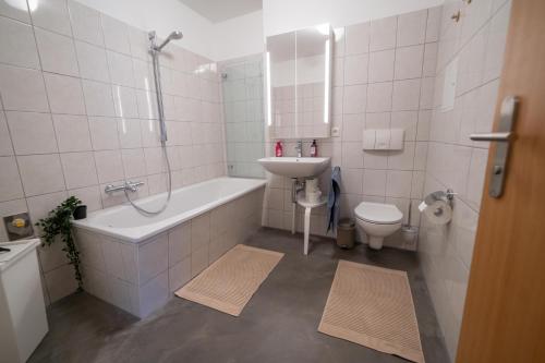 een badkamer met een wastafel, een bad en een toilet bij FULL HOUSE Studios - Apartment French Touch in Zwickau