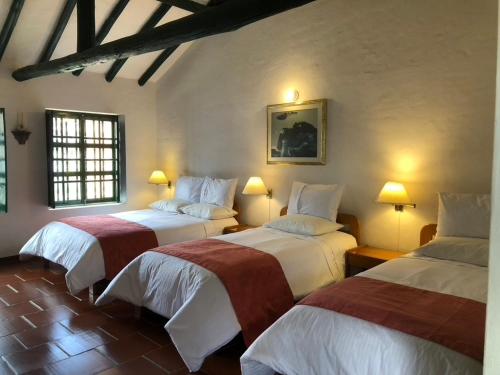 a bedroom with two beds in a room with lights at Hotel Hospederia San Carlos Villa De Leyva in Villa de Leyva