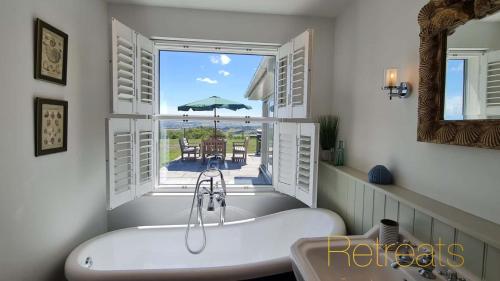 a bath tub in a bathroom with an open window at Hyfrydle in Mynytho