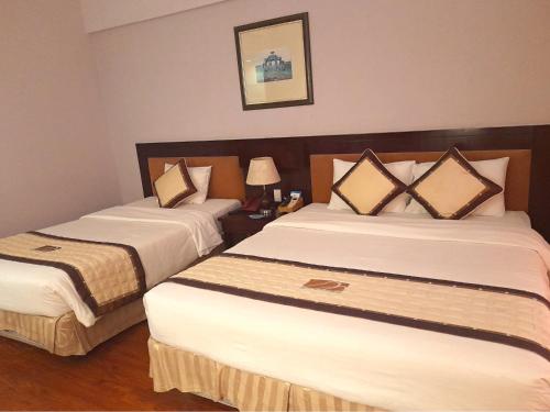 a hotel room with two beds with white sheets at Mondial Hotel Hue in Hue