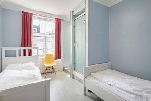 a bedroom with a bed, chair, and a window at Astor Victoria Hostel in London