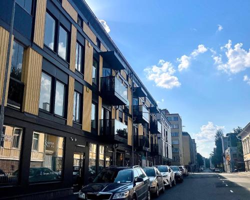 Una fila de autos estacionados en una calle al lado de un edificio en Modern 1 bedroom apartment in Central Kuopio, en Kuopio