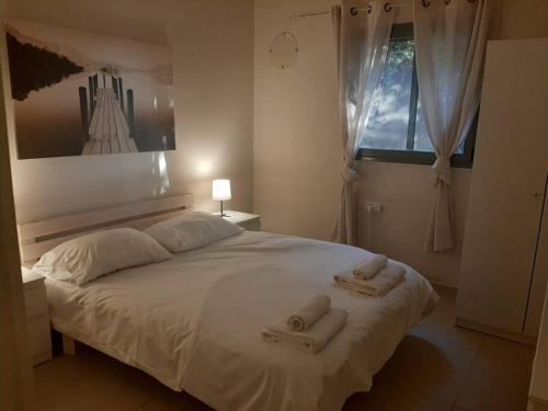 um quarto com uma cama branca e toalhas em A Spot on the Hill em Umm el Shuf