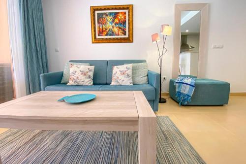 a living room with a blue couch and a table at Superb luxurious groundfloor 1 bedroom app on Mar Menor golf resort in Torre-Pacheco