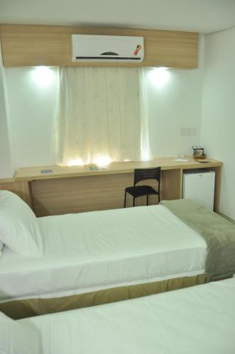 a bedroom with two beds and a desk with a chair at Arrey Express Hotel - Teresina in Teresina