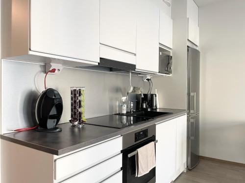 a kitchen with white cabinets and a black counter top at Modern 1 bedroom apartment in Central Kuopio in Kuopio
