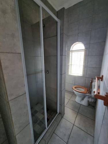 een badkamer met een toilet en een glazen douche bij Wallaces Place in Polokwane