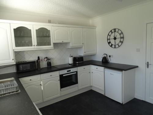 a kitchen with white cabinets and a clock on the wall at Discover Lewis and Harris in Stornoway