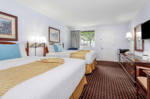 a hotel room with two beds and a flat screen tv at Travelodge by Wyndham Cape Cod Area in West Dennis