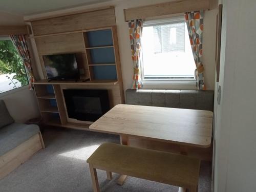 a living room with a table and a couch and a tv at New 2 bed holiday home with decking in Rockley Park Dorset near the sea in Lytchett Minster