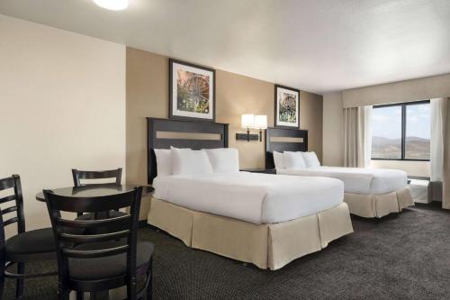Habitación de hotel con 2 camas, mesa y sillas en Baymont by Wyndham Elko, en Elko