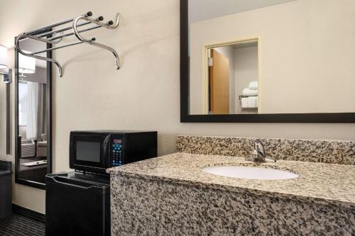 a bathroom with a sink and a microwave and a television at Baymont by Wyndham Elko in Elko
