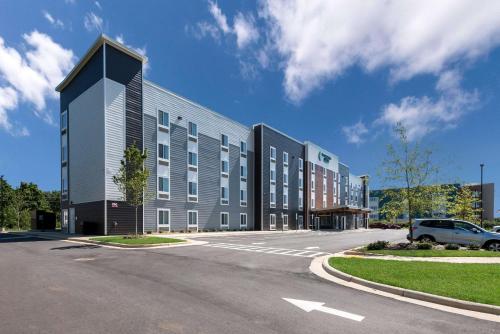 a large building with a car parked in a parking lot at WoodSpring Suites Greensboro - High Point North in Greensboro