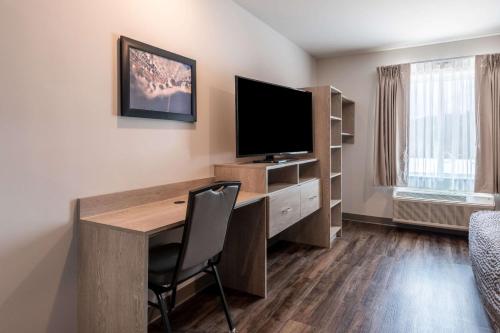 a room with a desk with a television and a chair at WoodSpring Suites Greensboro - High Point North in Greensboro