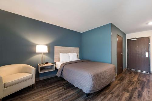 a blue bedroom with a bed and a chair at WoodSpring Suites Greensboro - High Point North in Greensboro