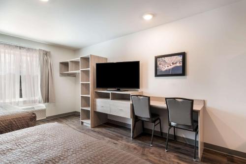 a room with a desk with two chairs and a television at WoodSpring Suites Greensboro - High Point North in Greensboro