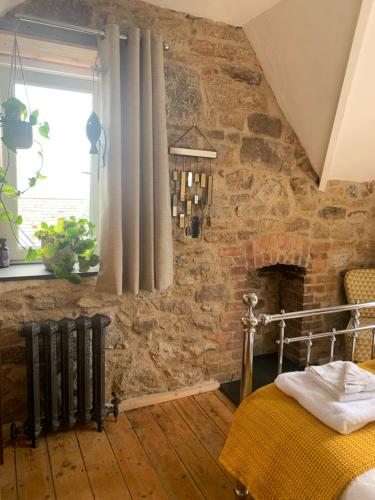 een slaapkamer met een stenen muur, een bed en een raam bij Shoreline in St Ives