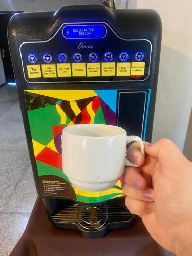 een persoon houdt een kopje in een koffiezetapparaat bij Hotel Panorâmico in Penha