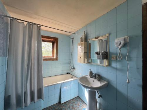 a blue tiled bathroom with a sink and a shower at MARIMO in Kutaisi