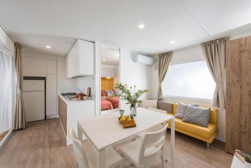 a kitchen and a living room with a white table and chairs at Camping Barco Reale in Lamporecchio