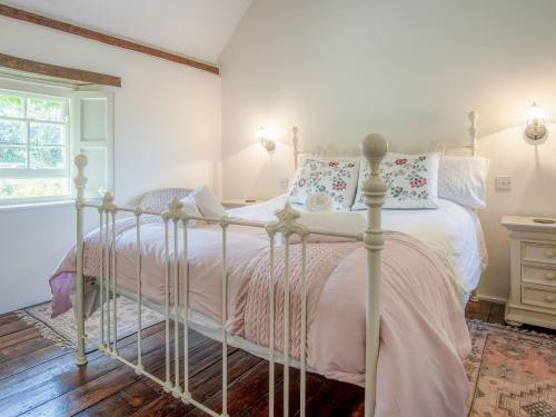 a bedroom with a white bed with pink sheets at Primrose Cottage - HW7100 in Amroth