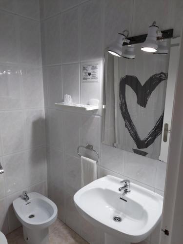 a bathroom with a white sink and a heart painting on the mirror at Hotel Cervantes in Mahora