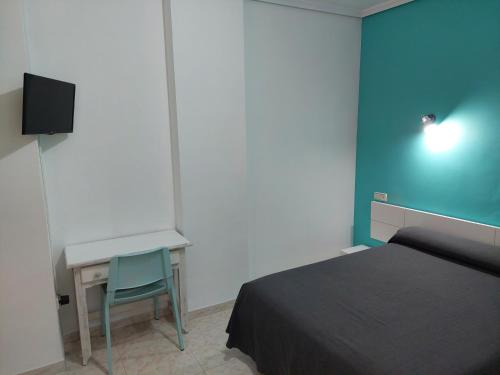 a bedroom with a bed and a desk and a television at Hotel Cervantes in Mahora