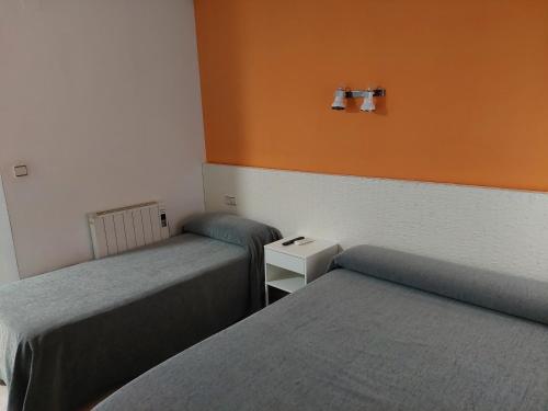 two beds in a room with orange and white walls at Hotel Cervantes in Mahora