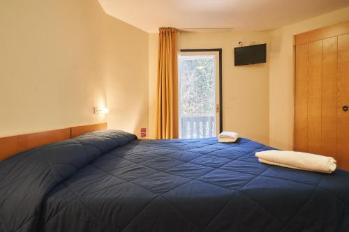 a bedroom with a blue bed with a window at Hotel Dolomiti in Brentonico