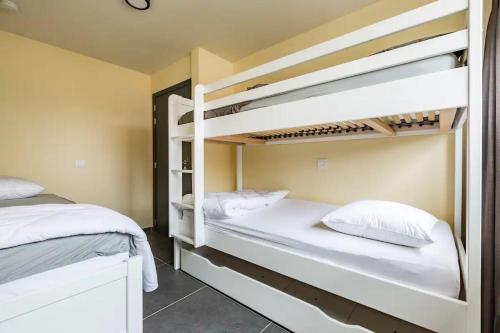 1 Schlafzimmer mit 2 Etagenbetten und weißen Kissen in der Unterkunft L'eau de vie in Alveringem