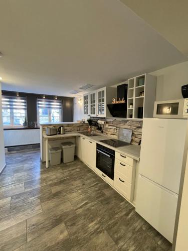 a large kitchen with white cabinets and wooden floors at Ferienwohnung Goslar am Marktplatz EG in Goslar