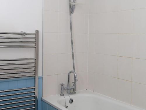 a bath tub with a shower head in a bathroom at Half Turn Cottage in Whitstable
