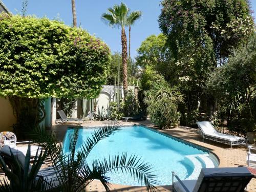 una piscina en un patio con palmeras en Riad El Arsat & Spa, en Marrakech