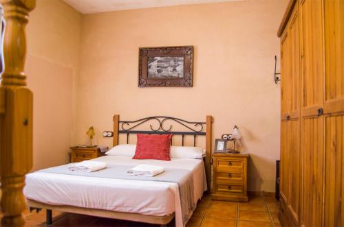 1 dormitorio con 1 cama con sábanas blancas y almohadas rojas en Casas Rurales Alhambra - Lagunas de Ruidera, en Alhambra