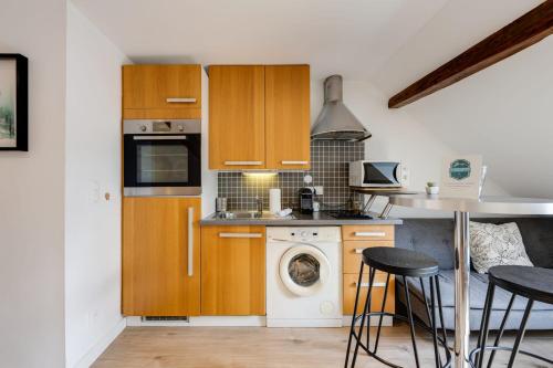 une cuisine avec des armoires en bois et une laveuse et une sécheuse dans l'établissement Duplex Vue Montagne - ideally located with its view, à Annecy