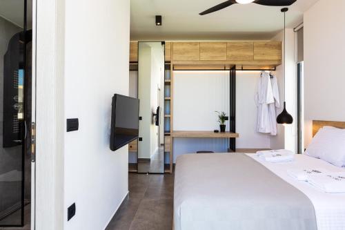 a bedroom with a white bed and a tv at Physis Villas - Metal & Wood in Pigi