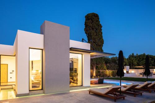 a villa with a swimming pool and some chairs at Physis Villas - Metal & Wood in Pigi