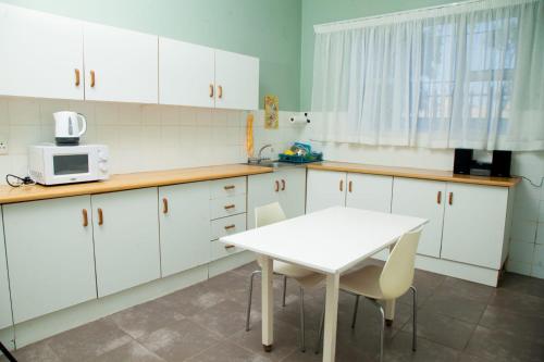 una cocina con armarios blancos y una mesa y sillas blancas. en Cozy Blue Guesthouse, en East London