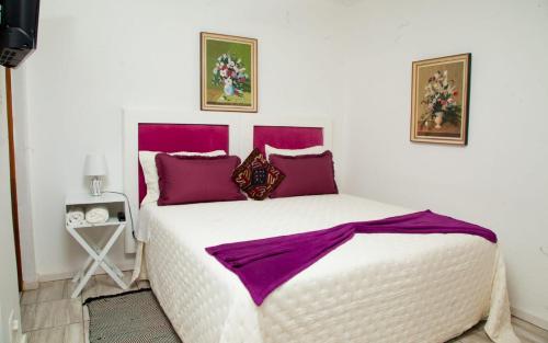 Un dormitorio con una gran cama blanca con almohadas moradas. en Cozy Blue Guesthouse, en East London