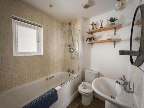 a bathroom with a tub and a sink and a toilet at Beach Boutique in Camber