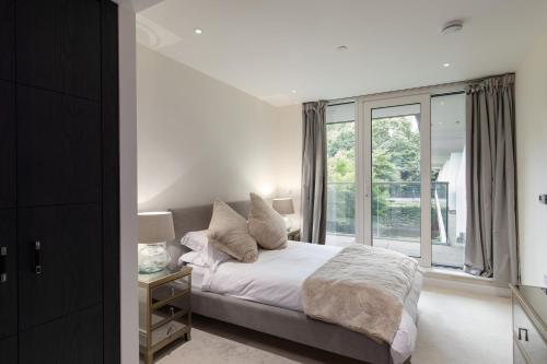 een slaapkamer met een bed en een groot raam bij Chelsea Cascade London Flat in Londen