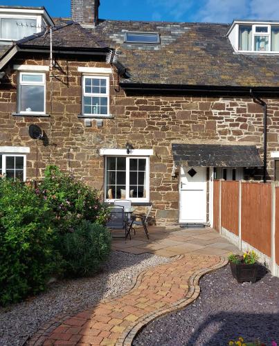 a brick house with a patio and a white door at Railway Cottage in Conwy