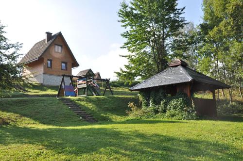 ein Haus und ein Spielplatz im Hof in der Unterkunft Domki Obertyny in Wetlina