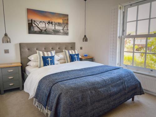 a bedroom with a large bed with a blue blanket at Seasalt Camber in Camber